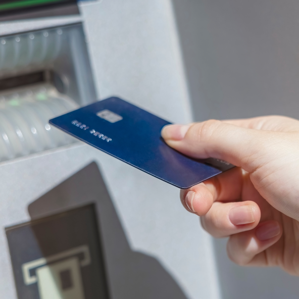 Osoba wkładająca granatową kartę do bankomatu