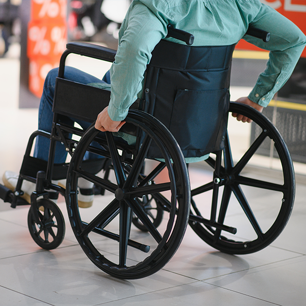 Osoba poruszająca się na wózku inwalidzkim w centrum handlowym, symbolizująca dostępność i mobilność osób niepełnosprawnych