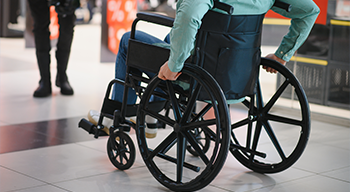 Osoba poruszająca się na wózku inwalidzkim w centrum handlowym, symbolizująca dostępność i mobilność osób niepełnosprawnych