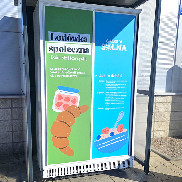 Zdjęcie przedstawia lodówkę społeczną w Galerii Solnej. Drzwi lodówki są w kolorze zielonym i niebieskim